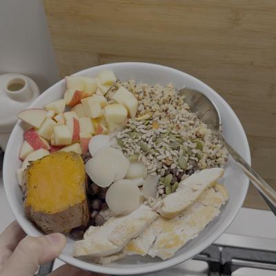 A nourishing grain bowl with sweet potato, chicken, apple, boiled egg, and mixed seeds